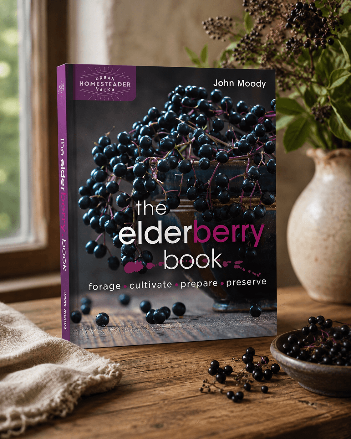 The Elderberry Book by John Moody beside a bowl of fresh elderberries